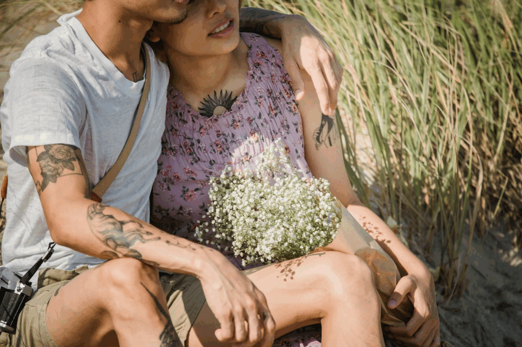 couple with tattoos hugging and holding flowers